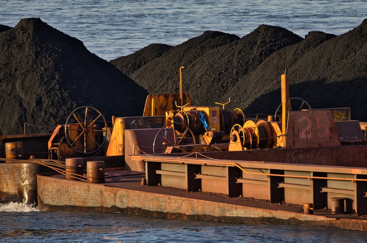 A cargo ship carrying coal on a river, showcasing inland waterway transportation and logistics.